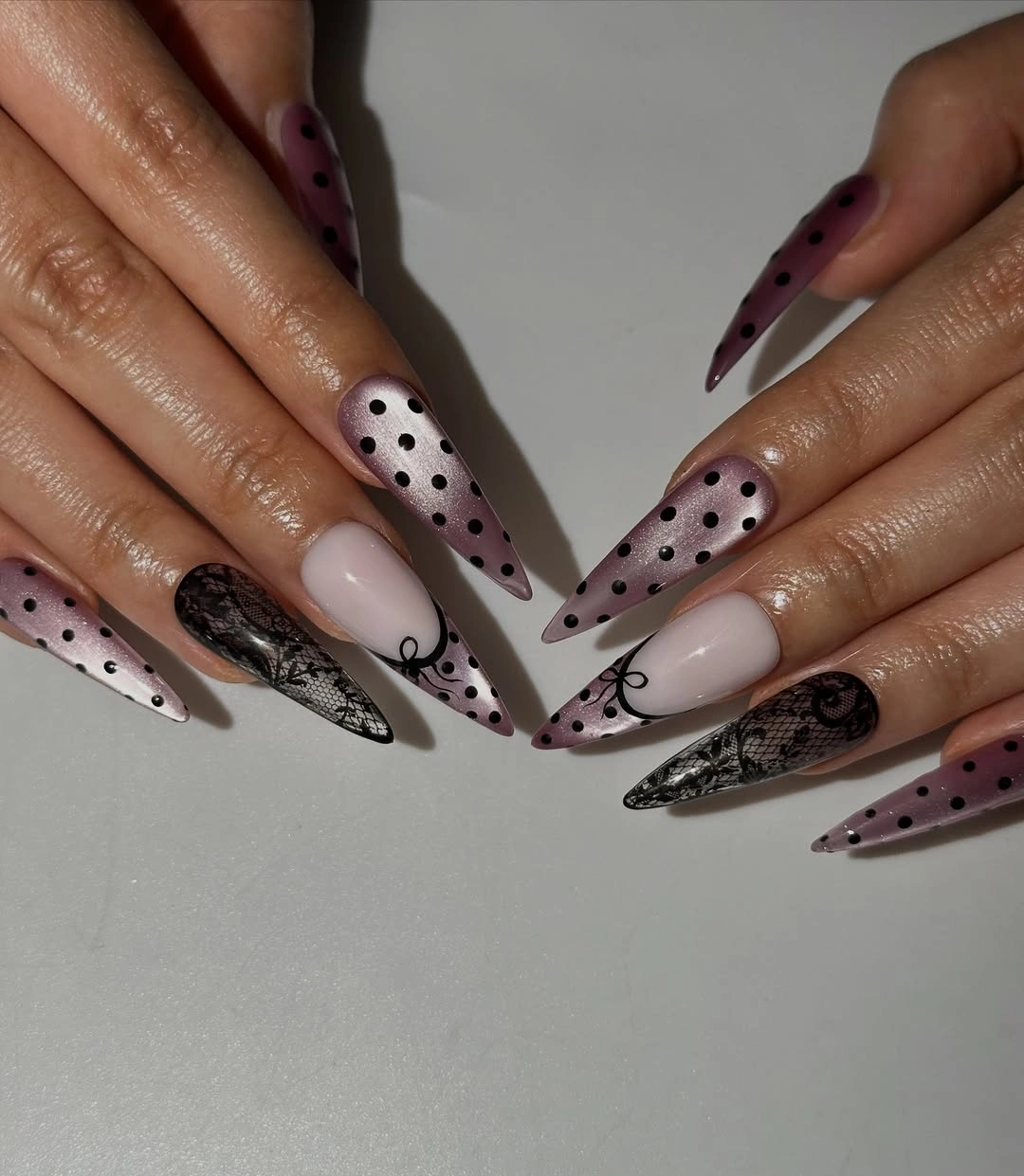 long pale pink pointed nails with diagonal white black dotted panels and dark accent