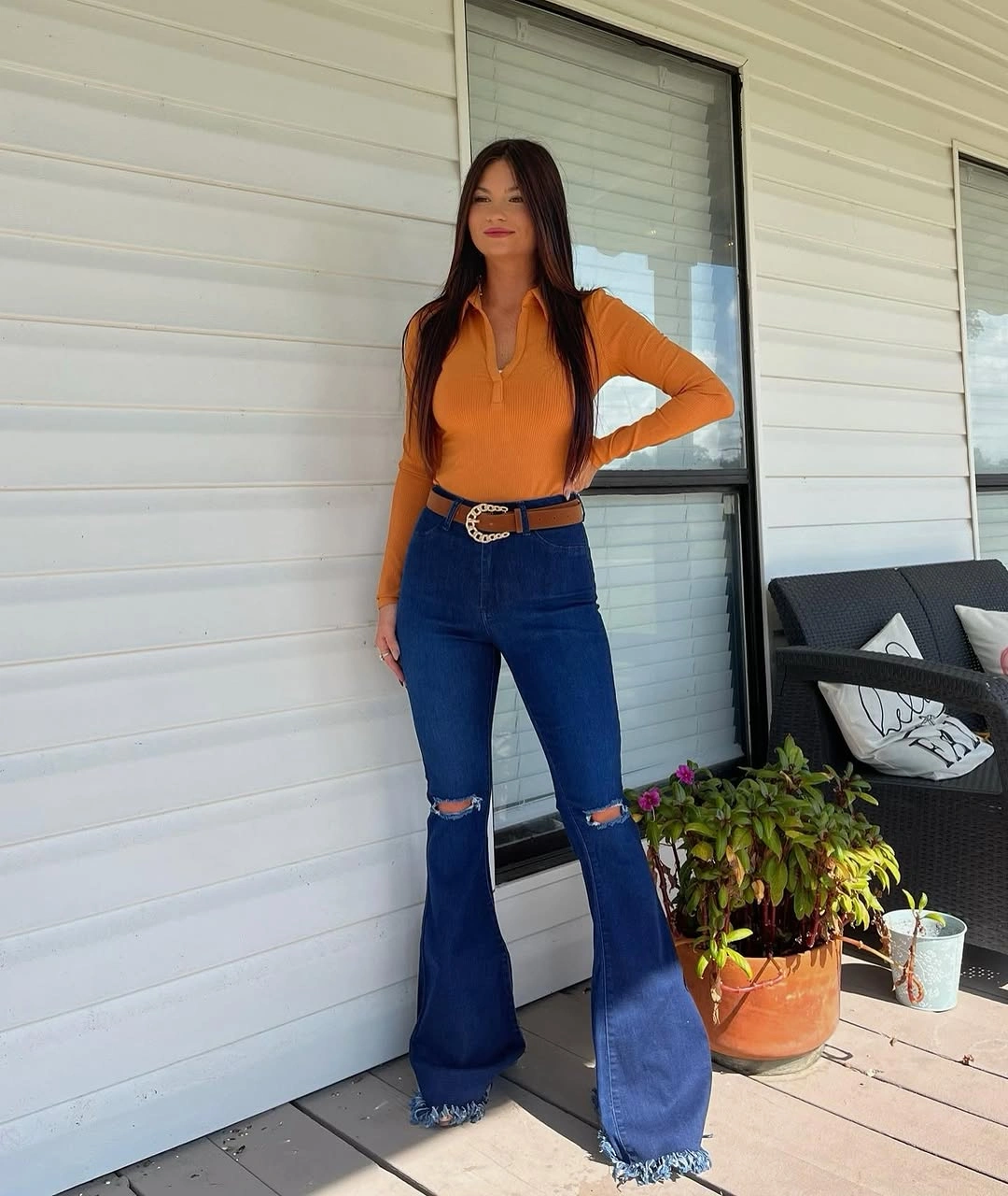 Fitted orange sweater with flared jeans and black belt