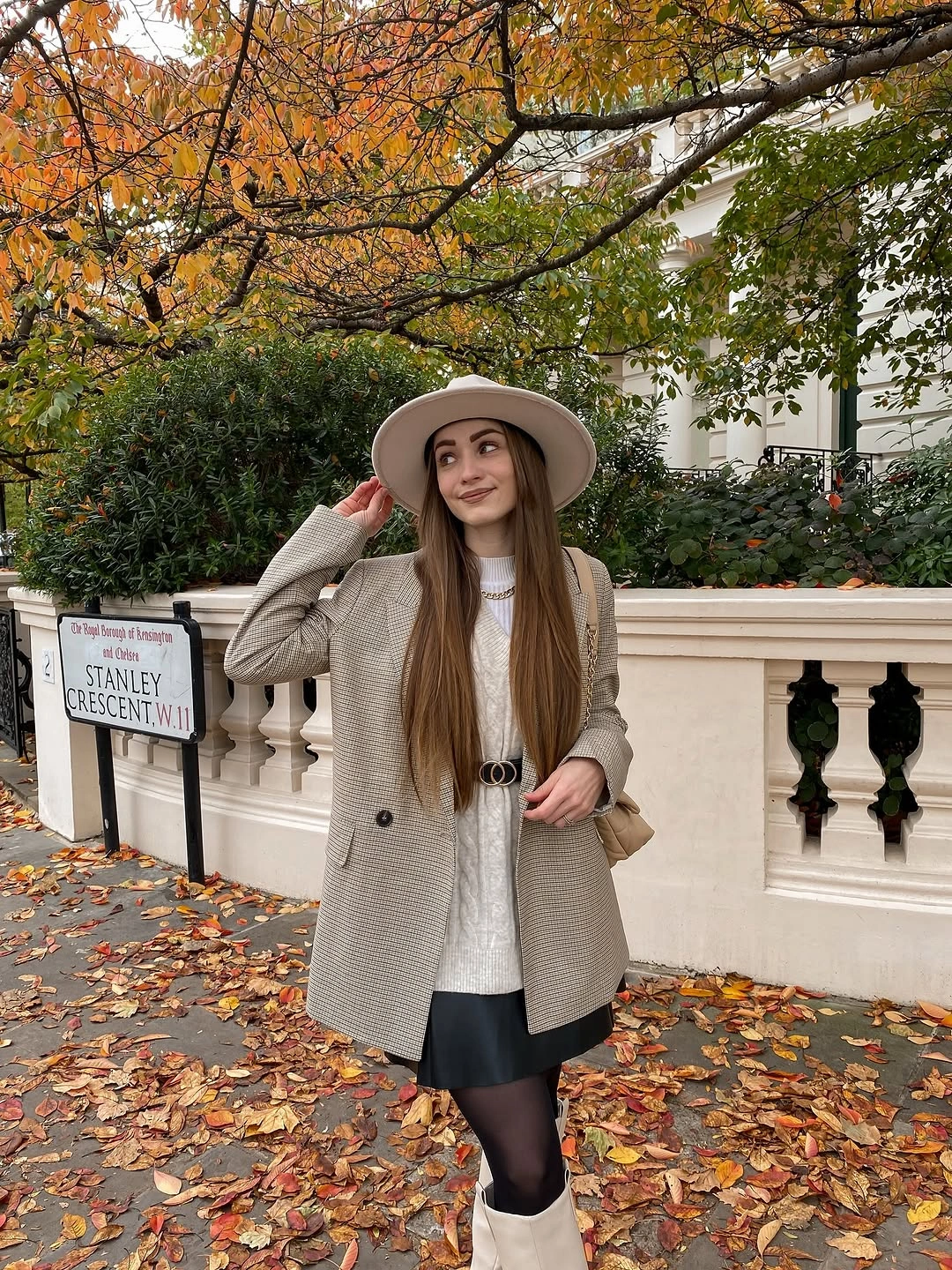 Herringbone coat over black skirt with pale wide-brim hat