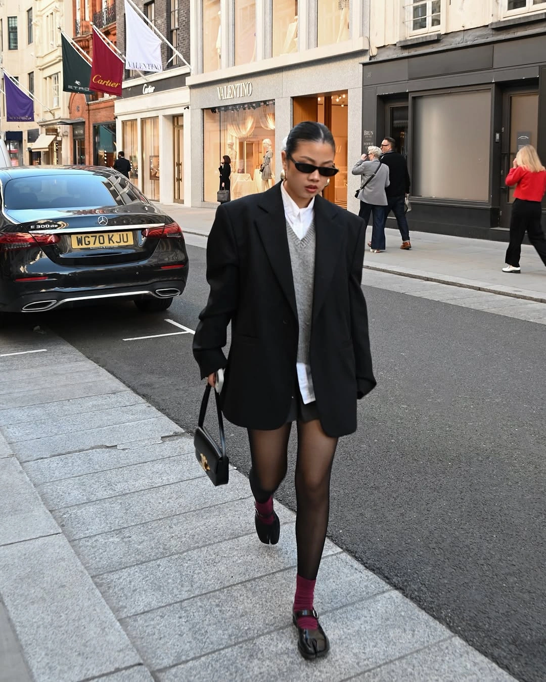 Oversized black blazer with white shirt black skirt and red shoes