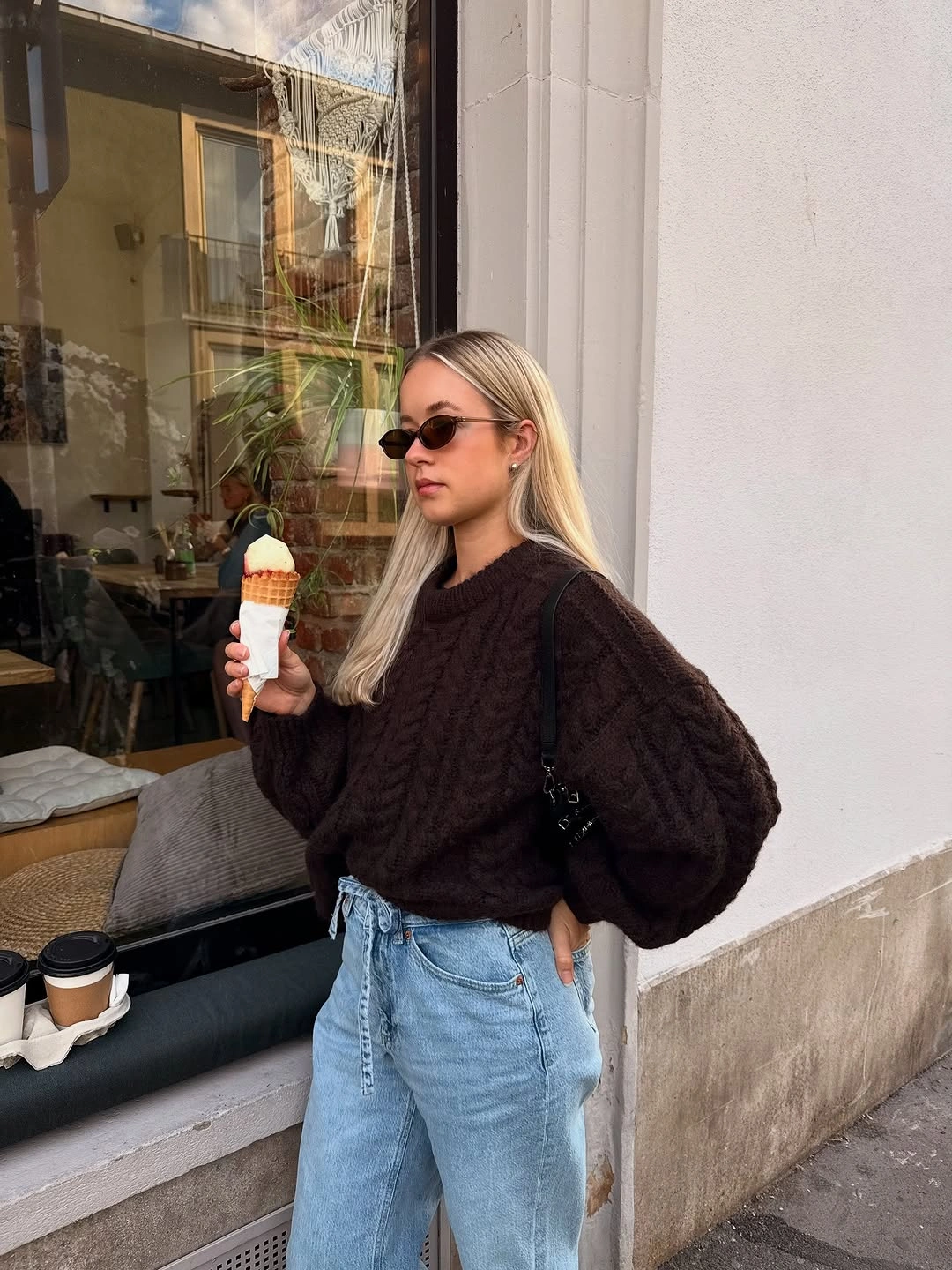 Dark textured sweater with pale blue jeans and sunglasses