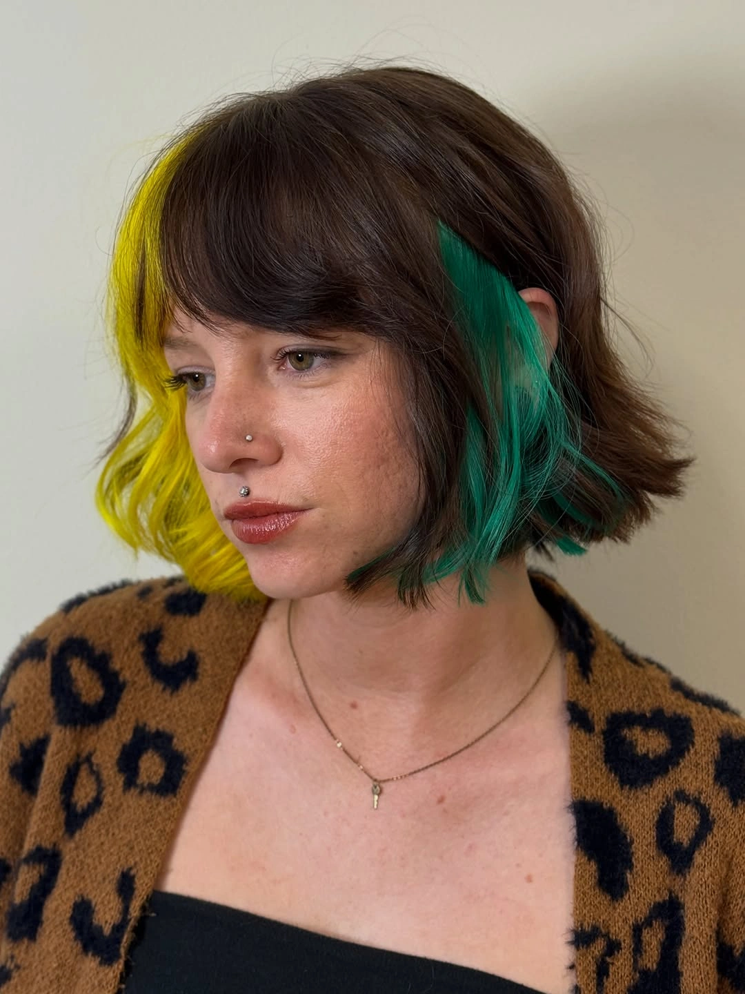 Short dark bob with bright green face framing streaks