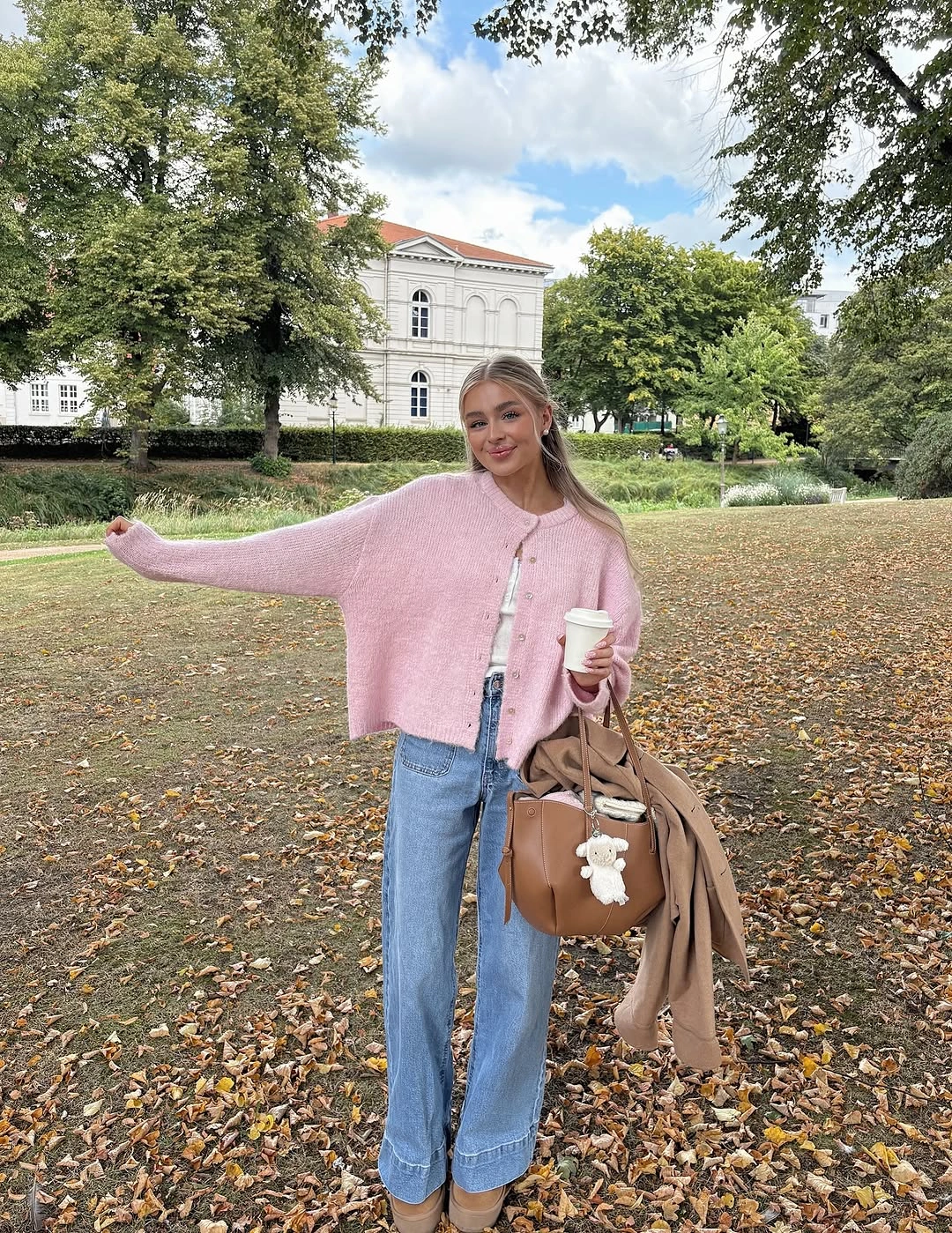 Soft pink oversized sweater with loose blue jeans and brown bag