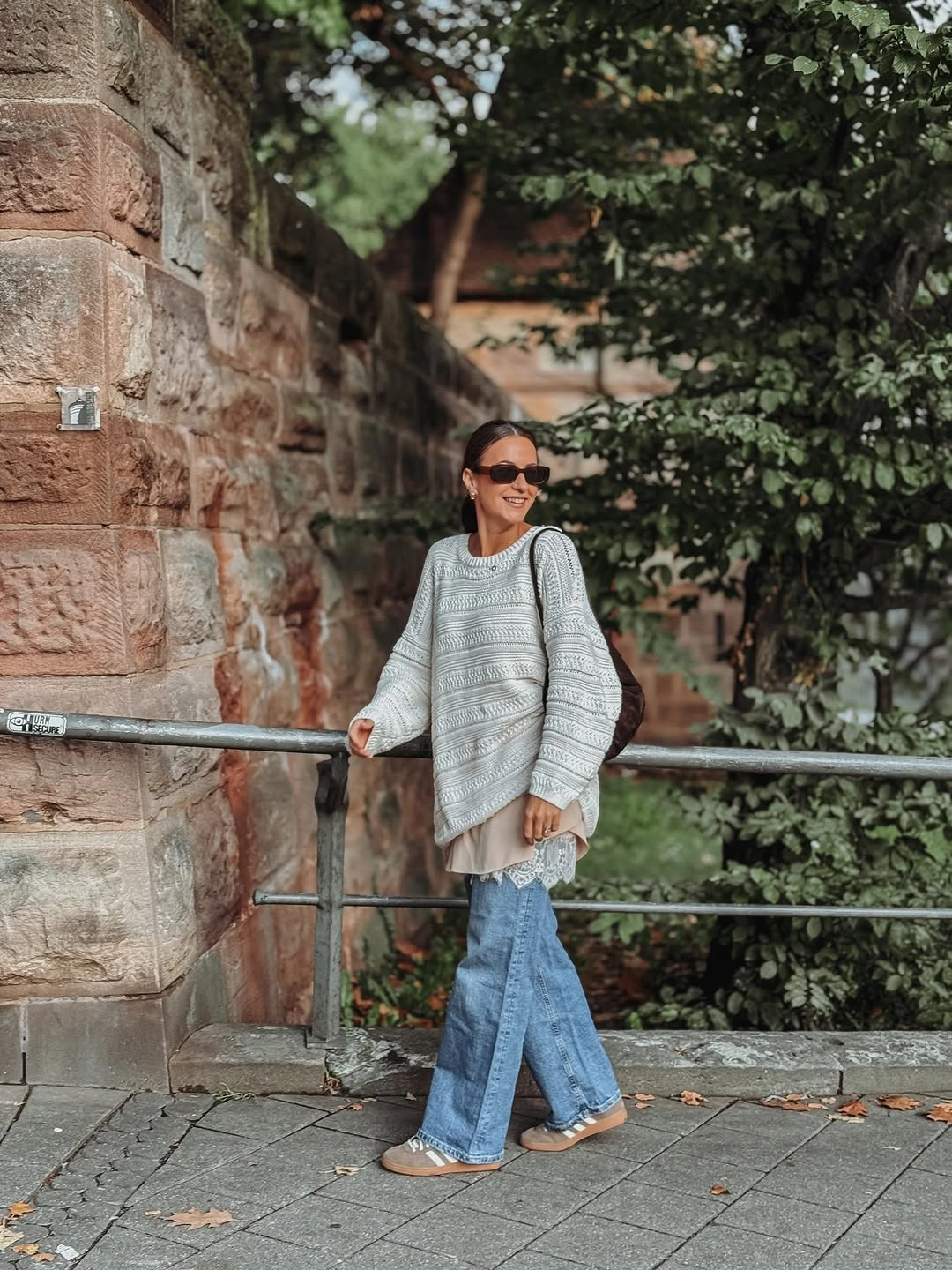 Chunky gray sweater with light flared jeans and sneakers