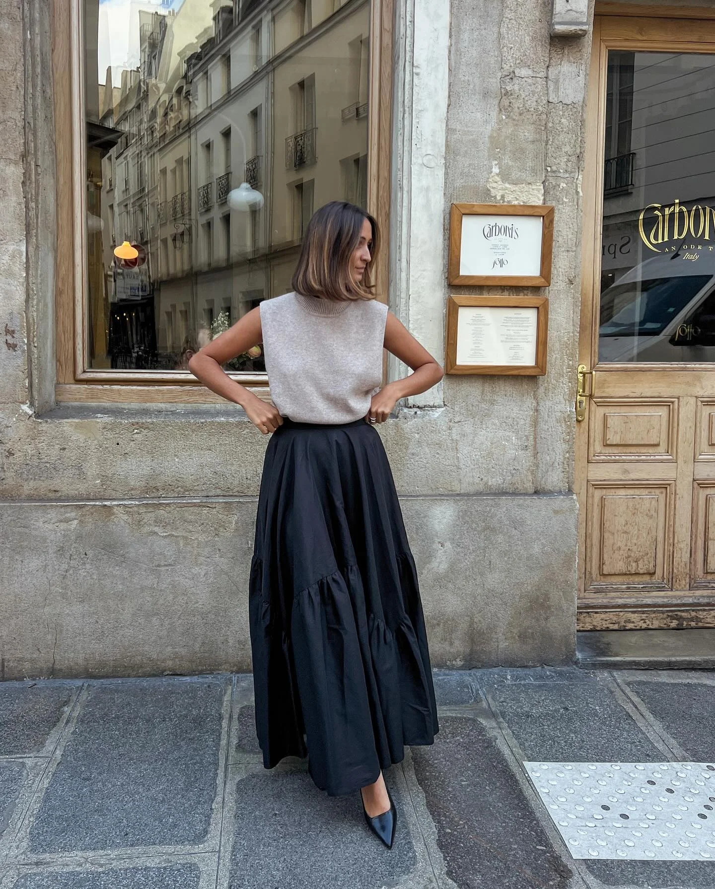 Cream knit top with full black skirt and brown shoulder bag