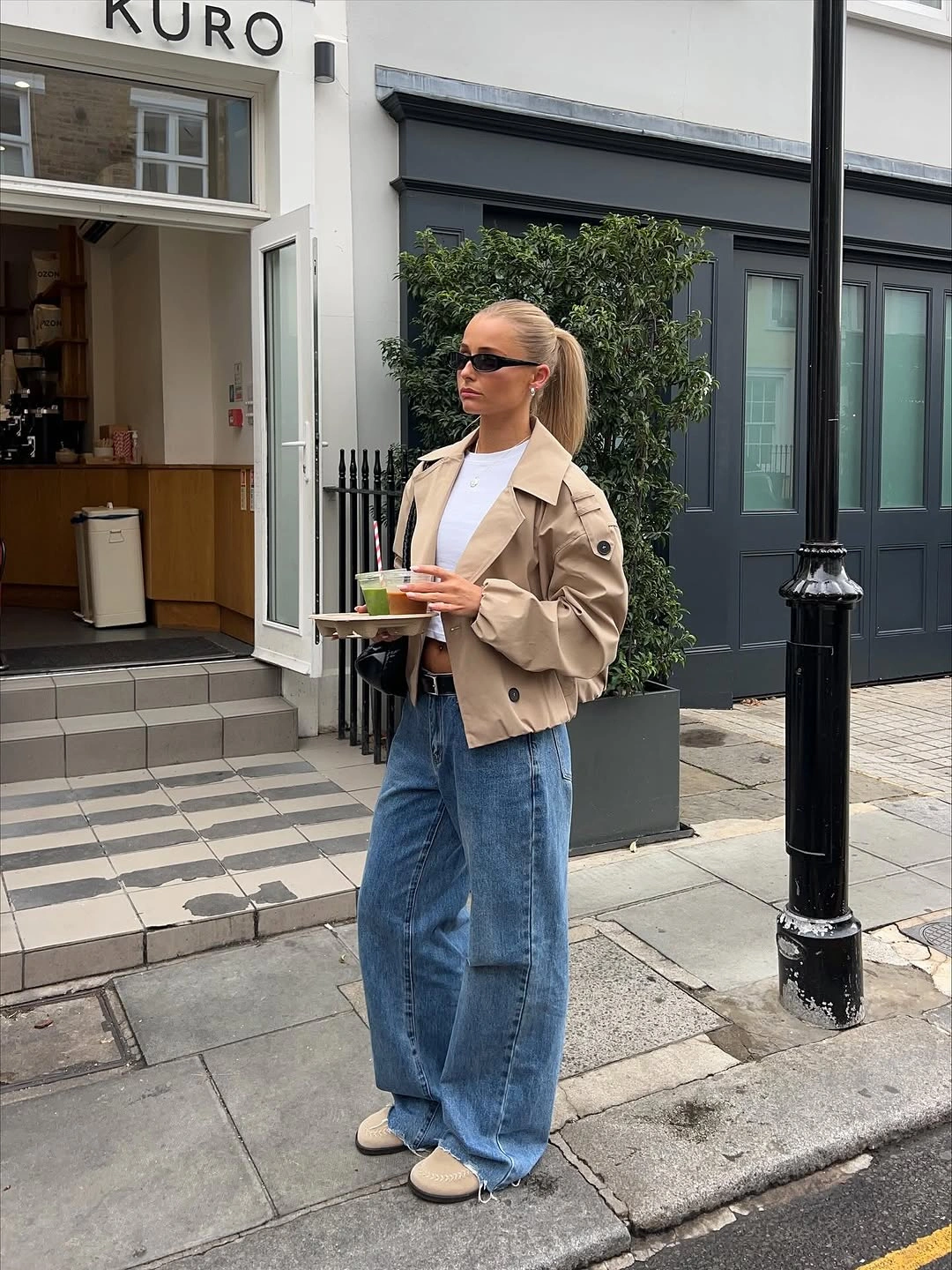Cropped beige jacket styled with wide blue jeans and pale sneakers
