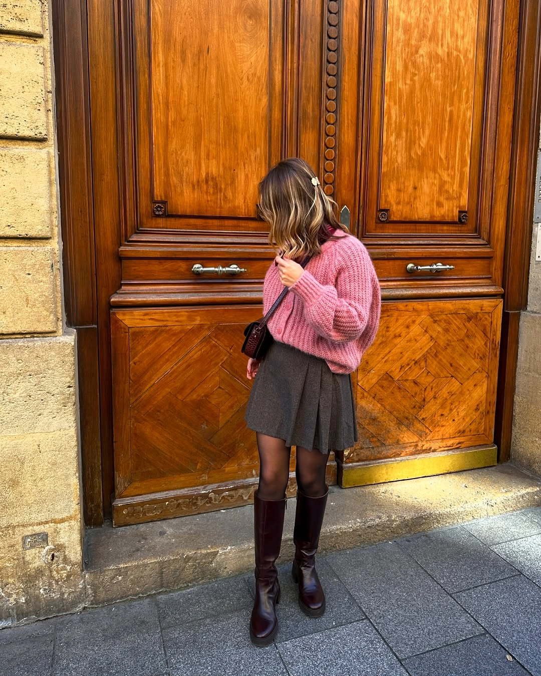 Pink knit sweater with gray pleated mini skirt and knee boots