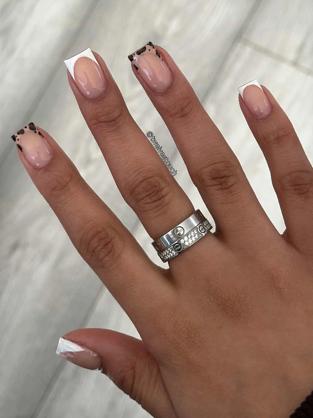 Short nude square nails with white French tips and dark dots