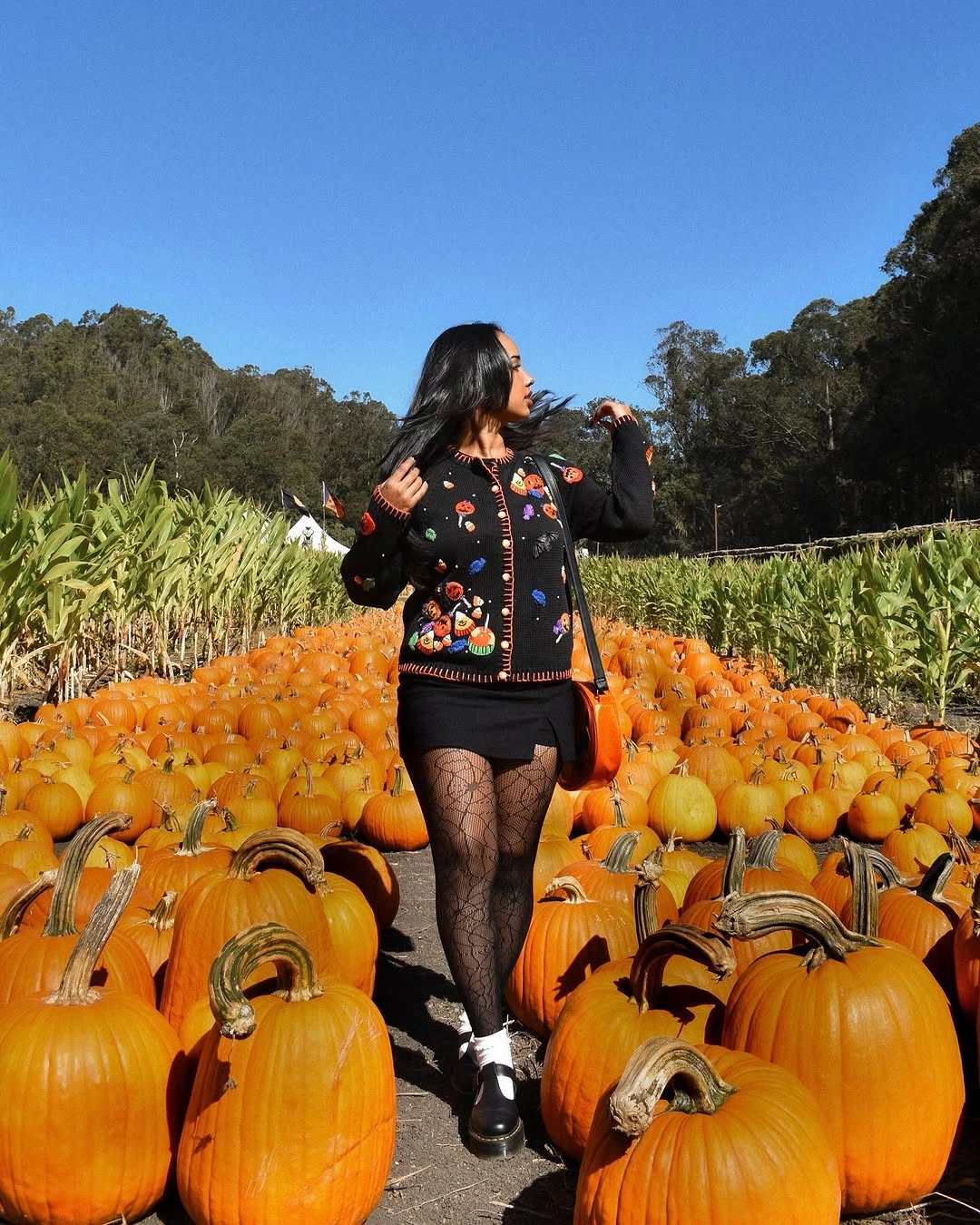 Haunted house Halloween cardigan with embroidered pumpkins, ghosts, and dark tights