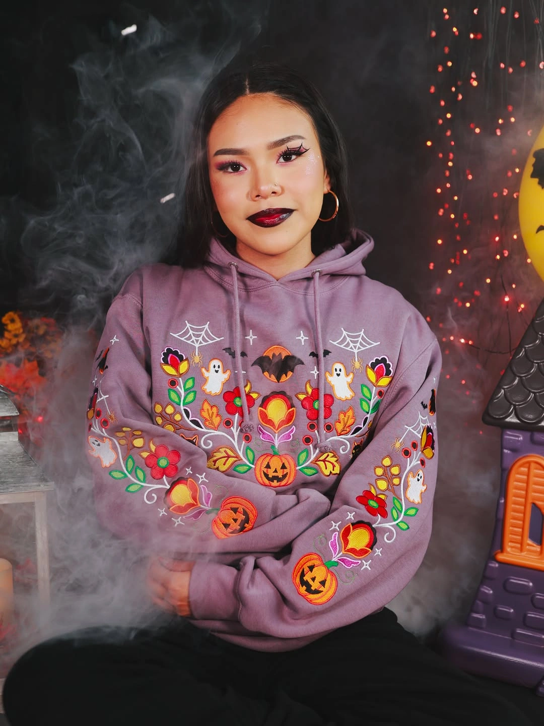 Pastel Halloween folk-art hoodie with spiders, pumpkins, flowers, and ghost motifs