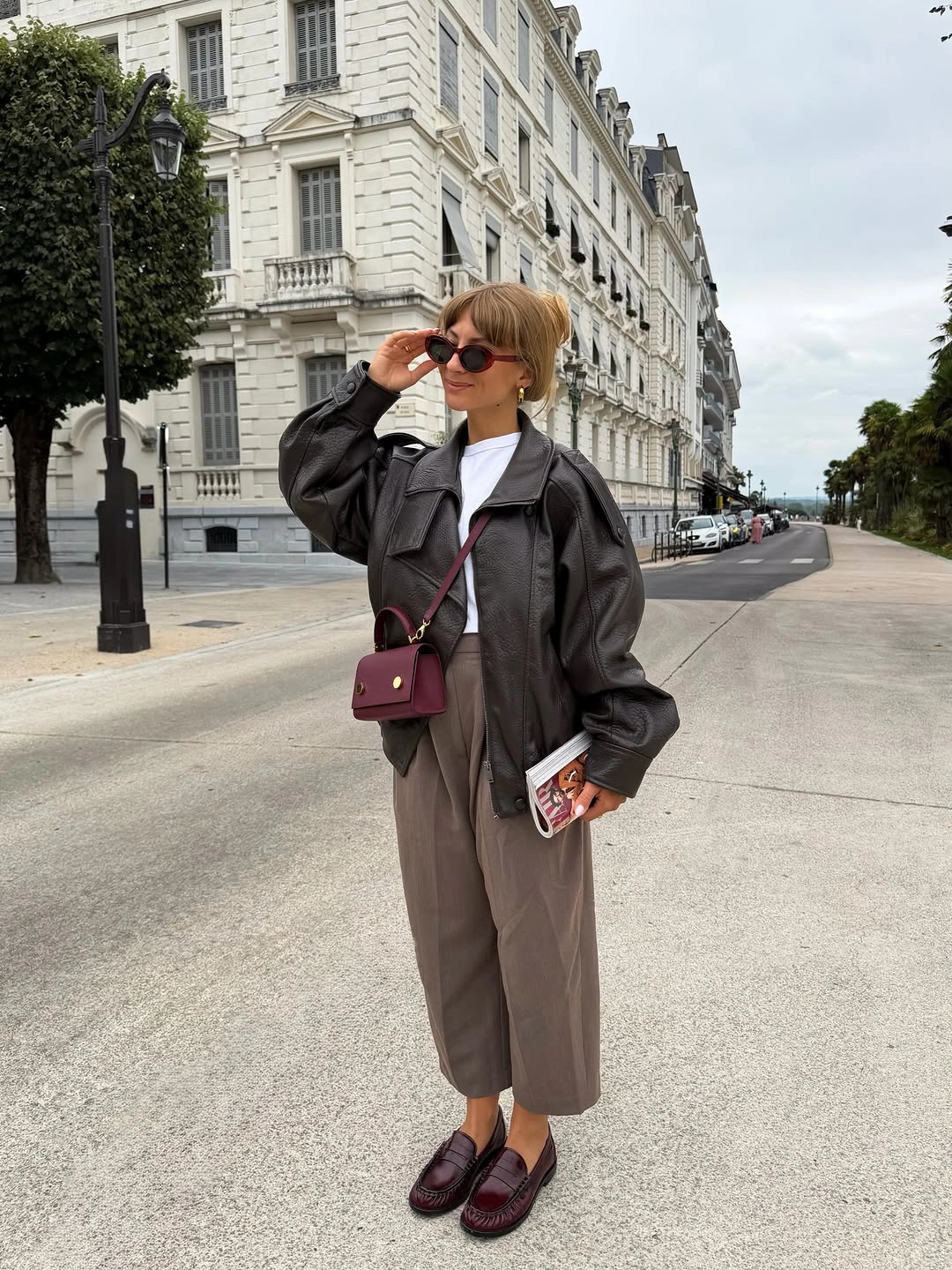 Dark leather-look jacket, white top, cropped brown trousers, burgundy loafers