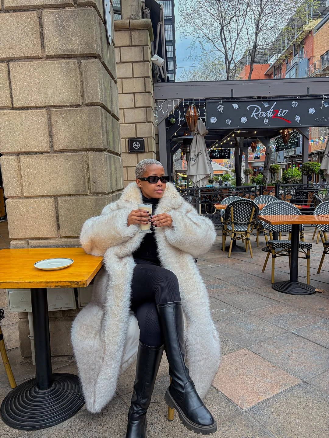 Cream fur-textured coat over black outfit with tall black boots