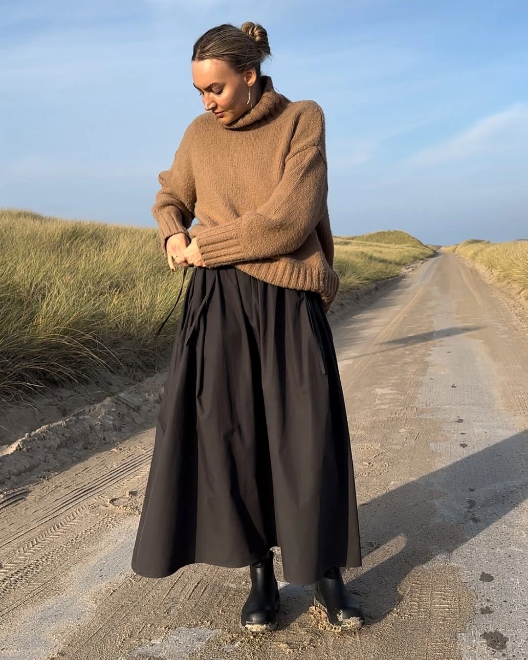 Brown turtleneck with full black ankle-length skirt and black boots