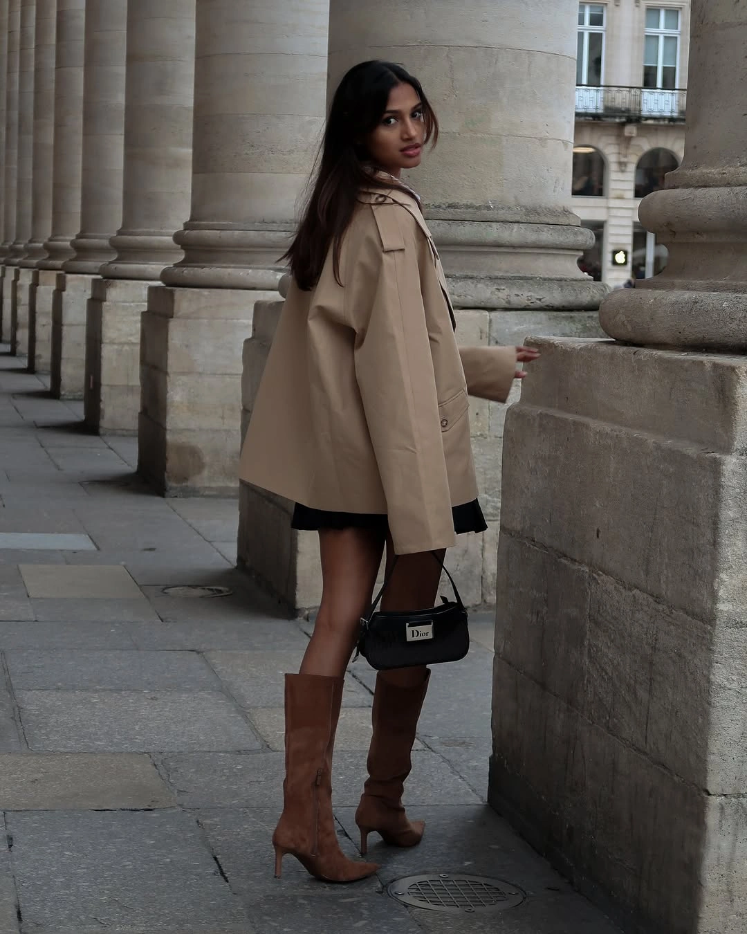 Tan jacket with short black skirt and tall brown boots