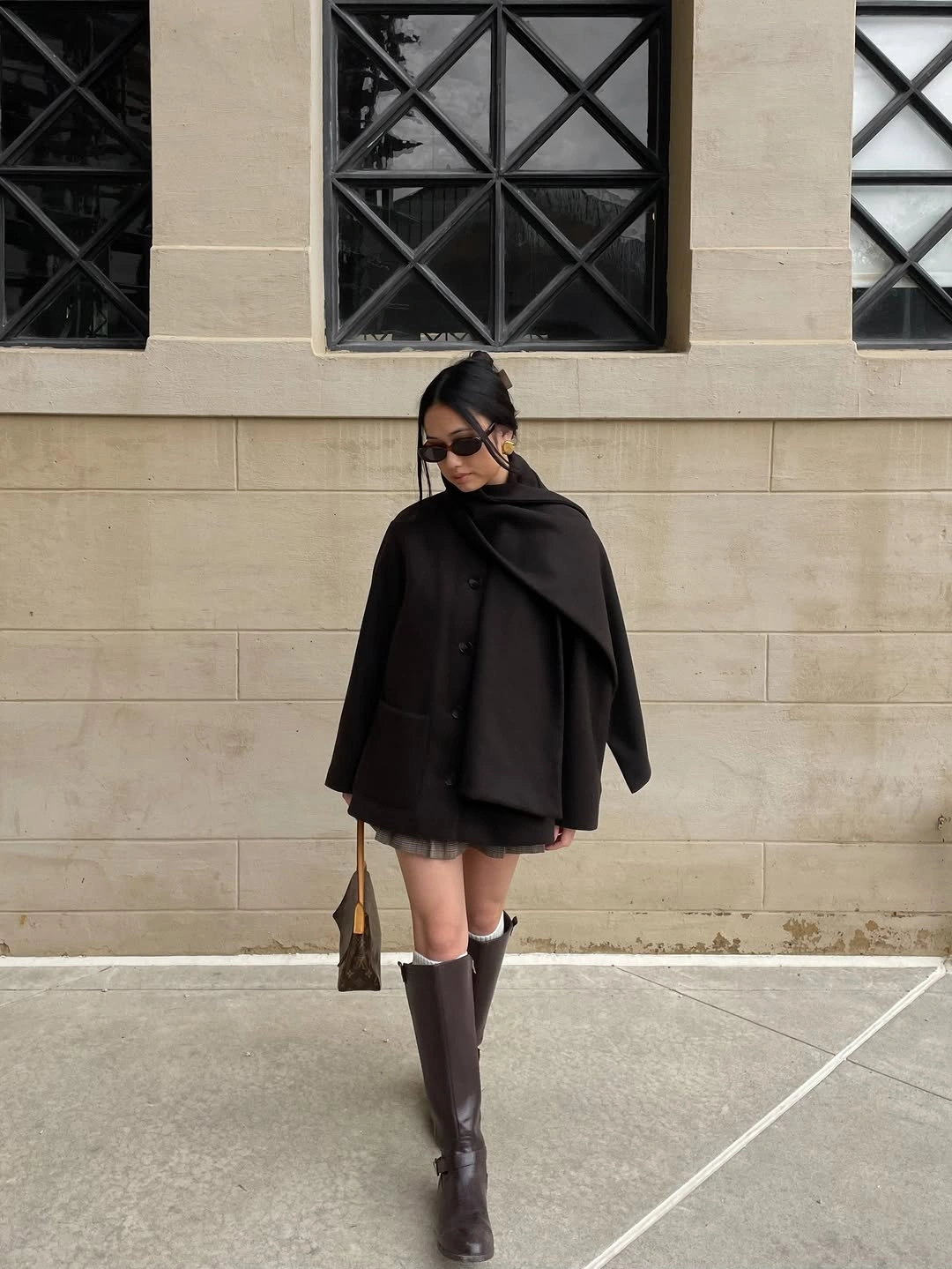 Black cape-like layer, short gray hem, tights, and tall boots