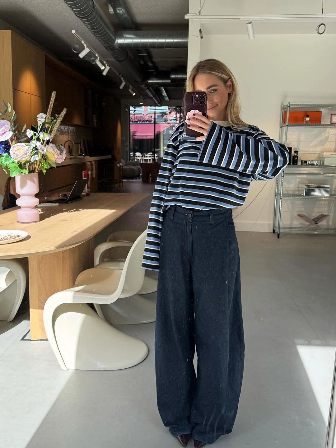 Striped long-sleeve top tucked into extremely wide dark-blue jeans