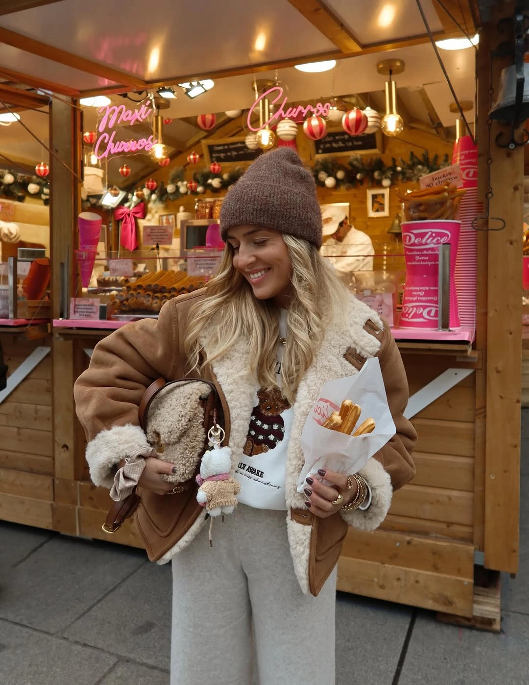 Brown shearling-style jacket with gray wide trousers and brown beanie