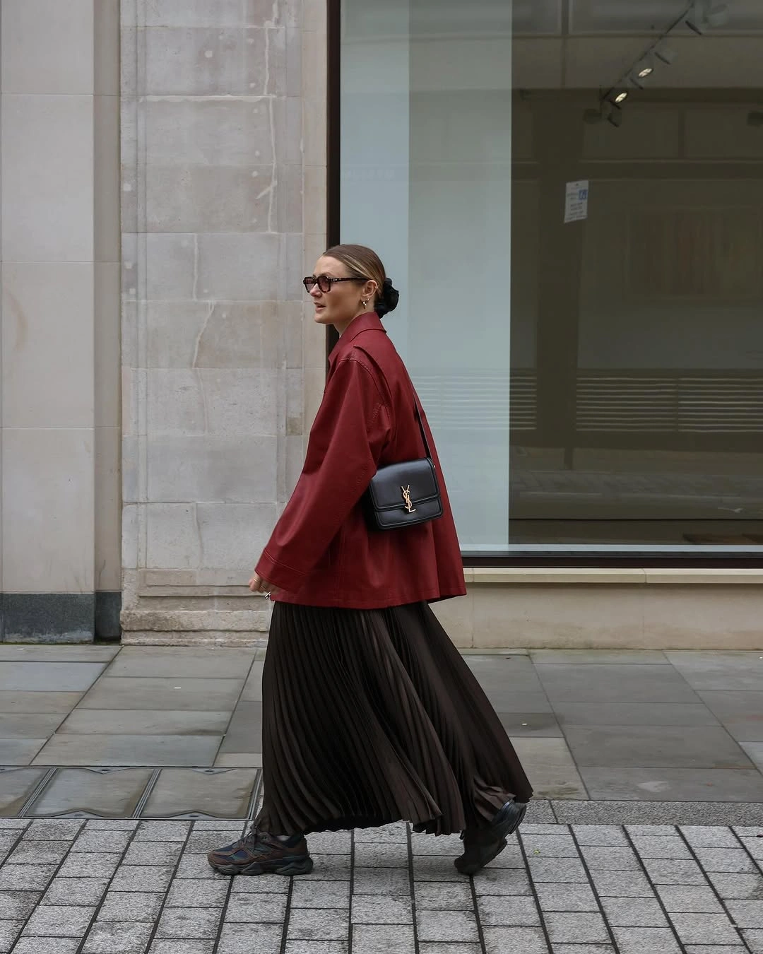 Deep-red jacket with long black pleated skirt and black accessories