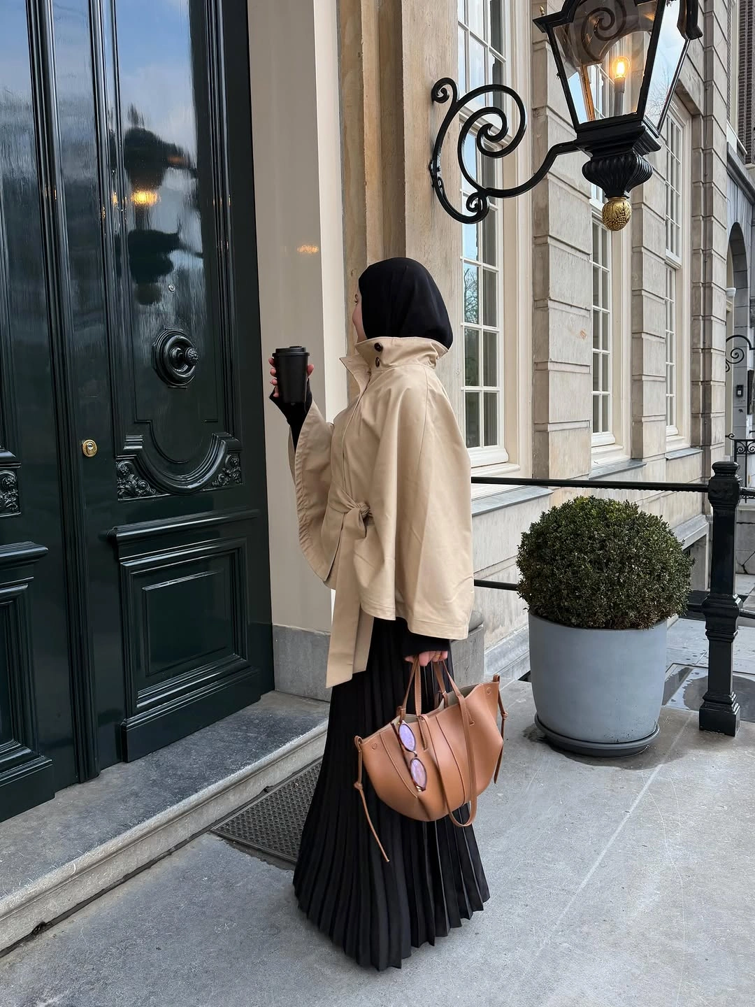 Cream tied jacket with long black pleated skirt and tan tote