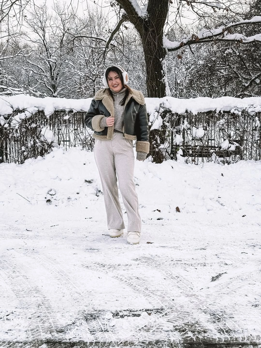 Olive-brown shearling-style jacket with pale trousers and sneakers