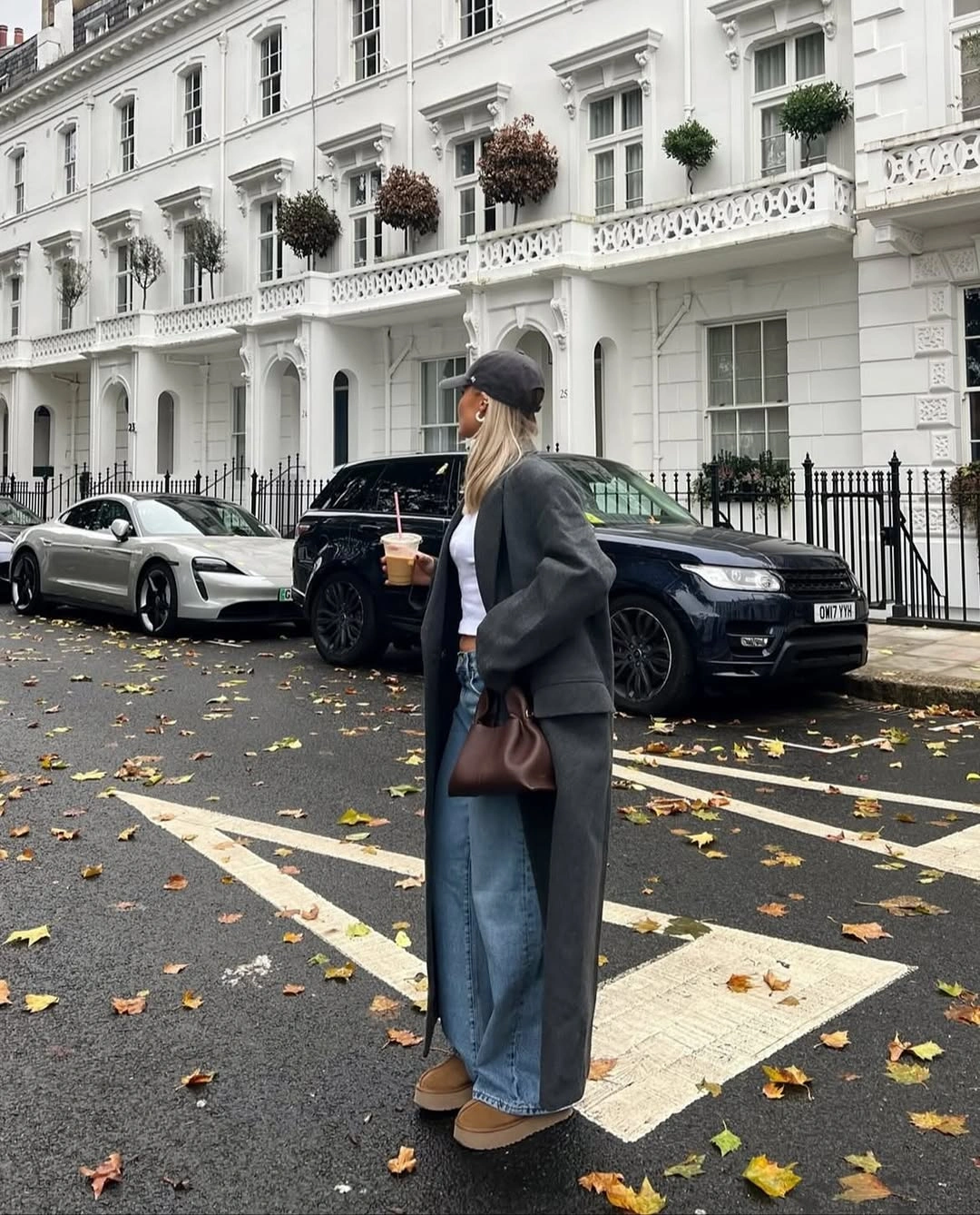 Charcoal coat, short white top, wide jeans, cap, and tan footwear