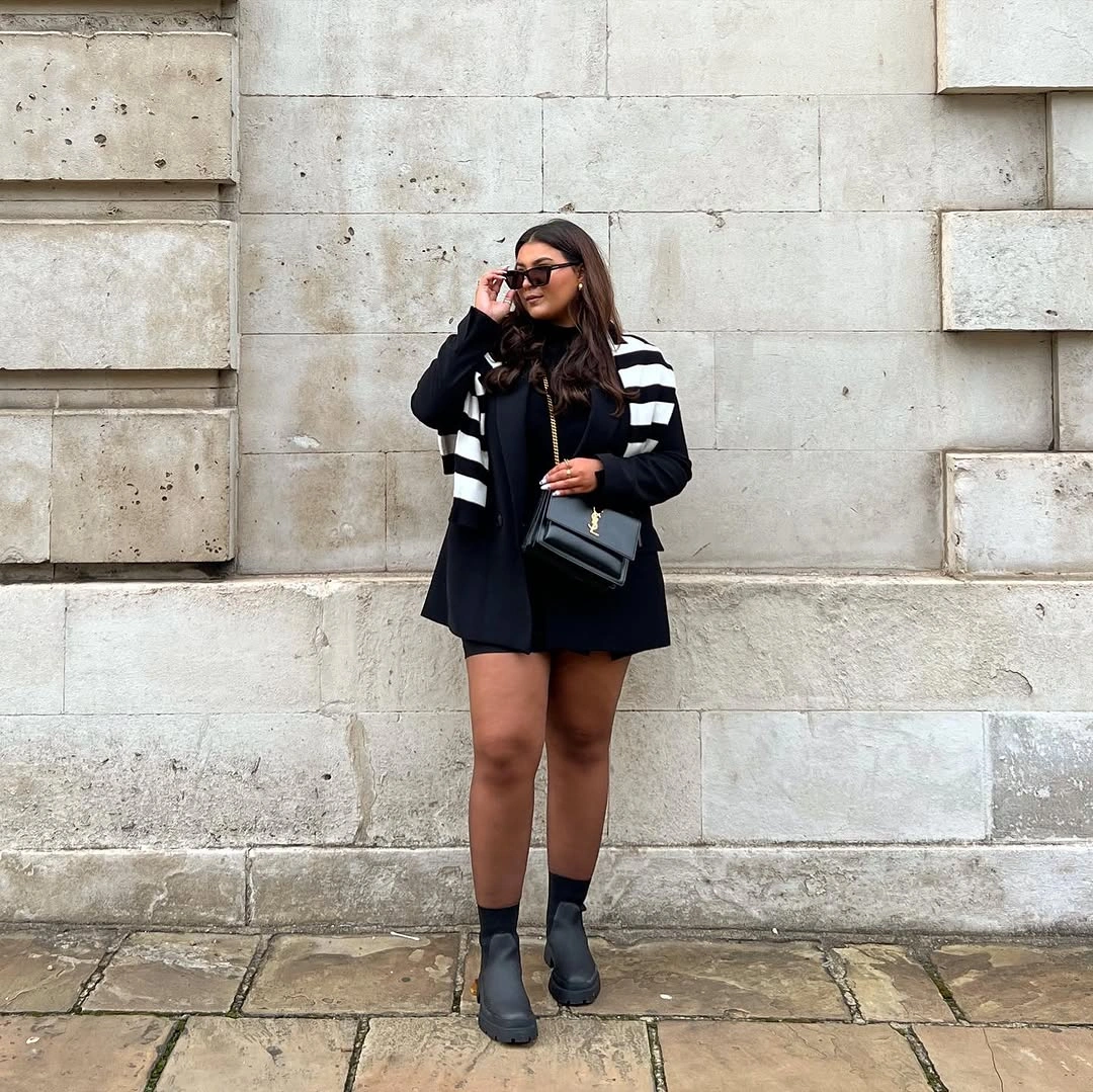 Black blazer with striped shoulder knit, dark socks, and ankle boots