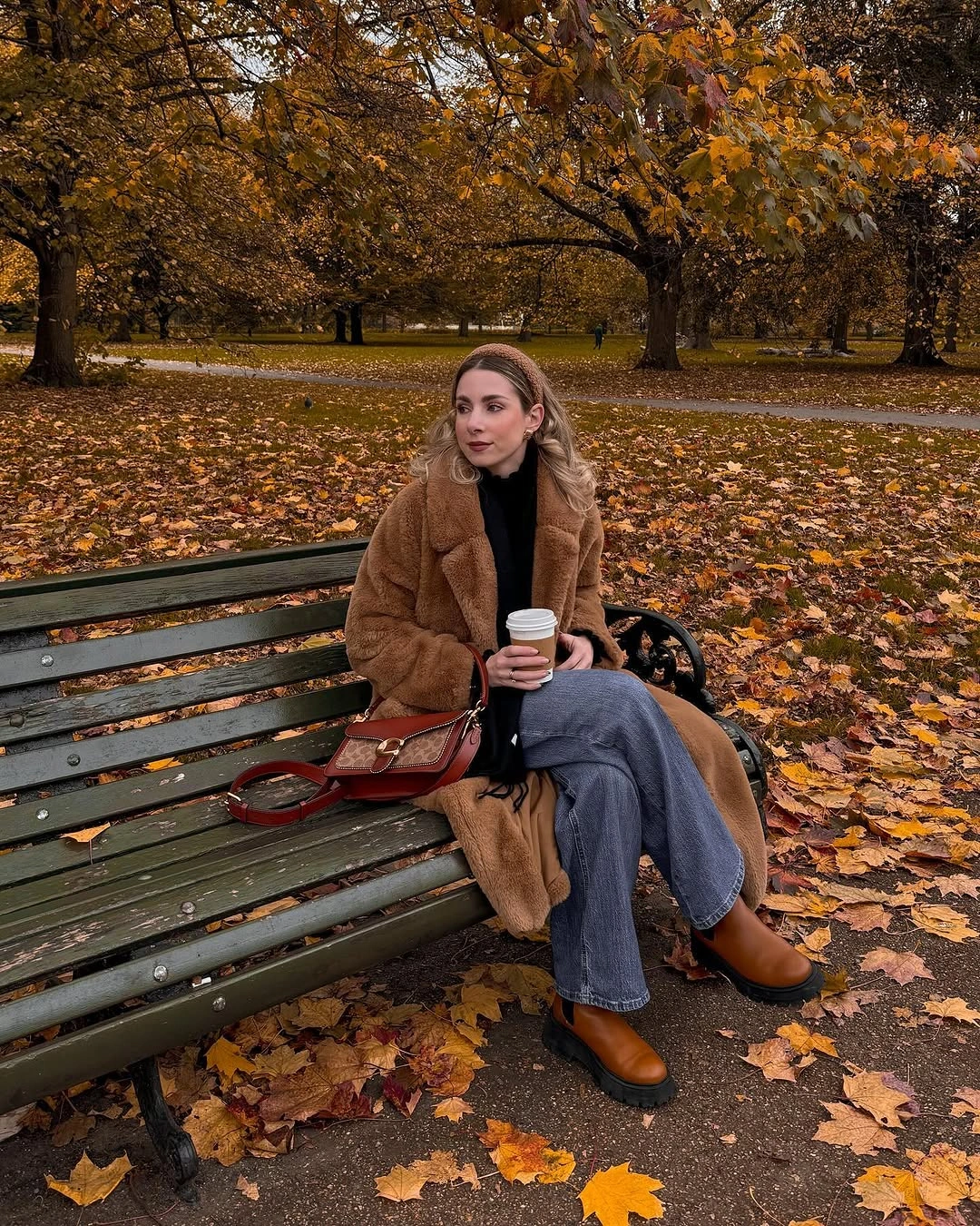 Camel-brown textured coat with black top, blue jeans, brown shoes, and bag