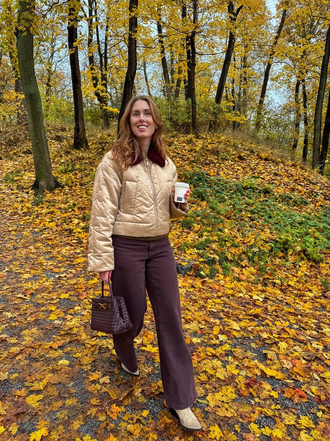 Light quilted jacket, burgundy-brown trousers, pale boots, and dark handbag