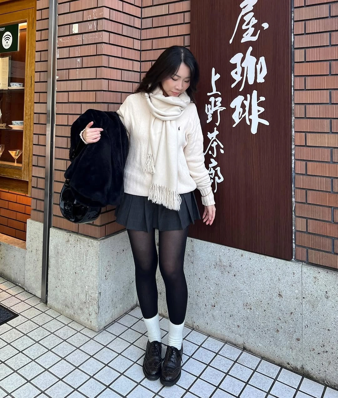 Ivory sweater and scarf with black pleated mini, tights, socks, and shoes