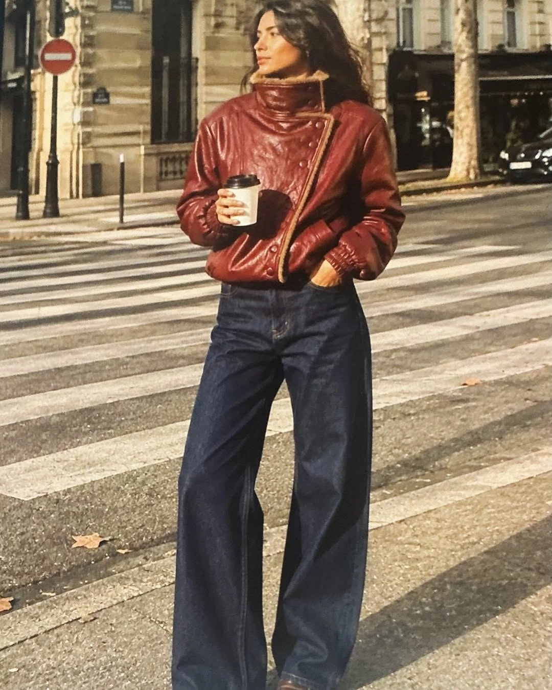 Red-brown glossy jacket with wide dark jeans and crossbody strap
