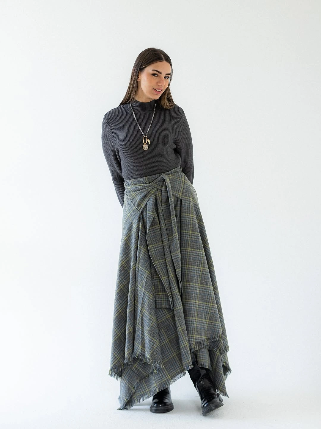 Gray ribbed turtleneck with asymmetric plaid skirt and black shoes