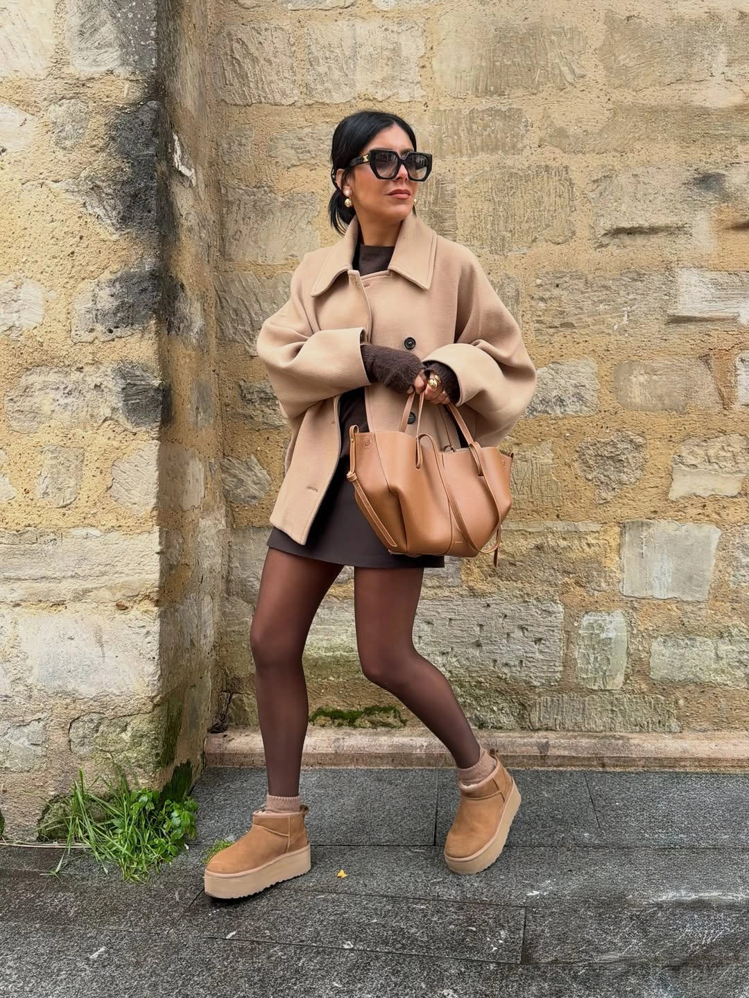 Camel coat with dark short layer, tights, and tan platforms