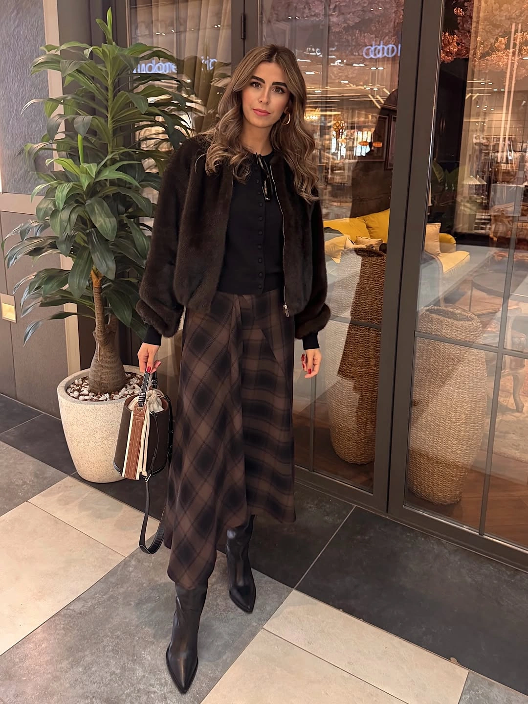 Dark jacket with brown plaid midi, pointed boots, and structured bag