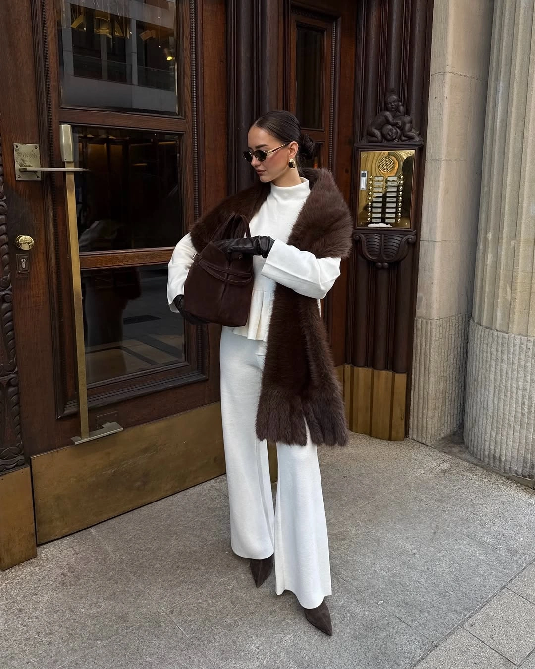 Dark brown textured vest over white top and wide white trousers