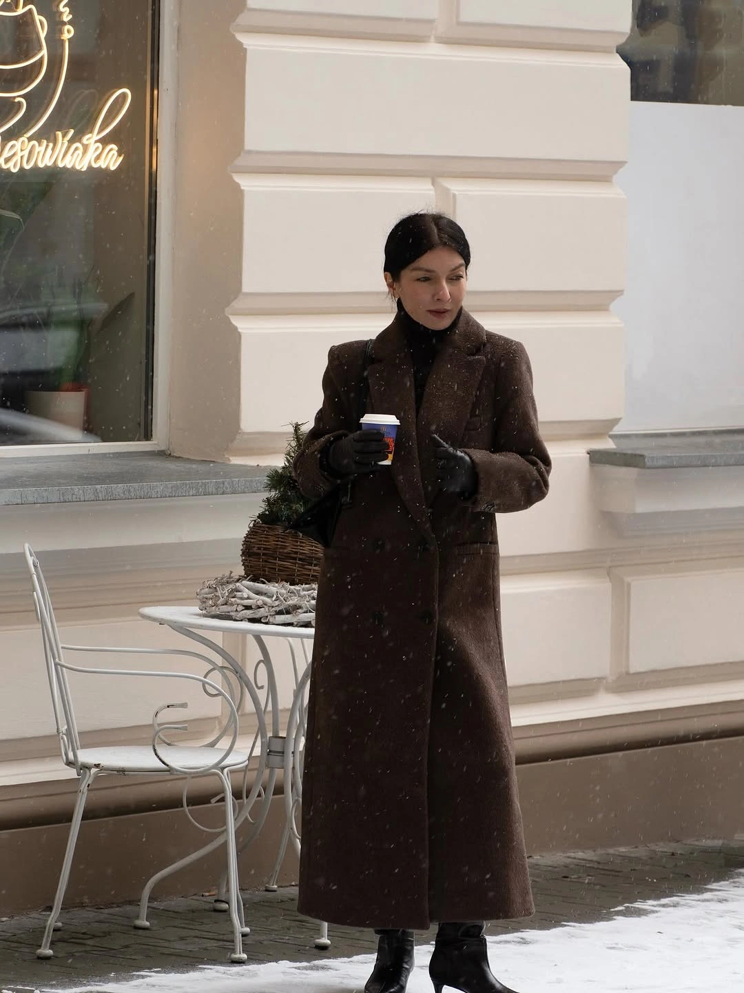 Long dark brown coat with gloves knee boots and small bag