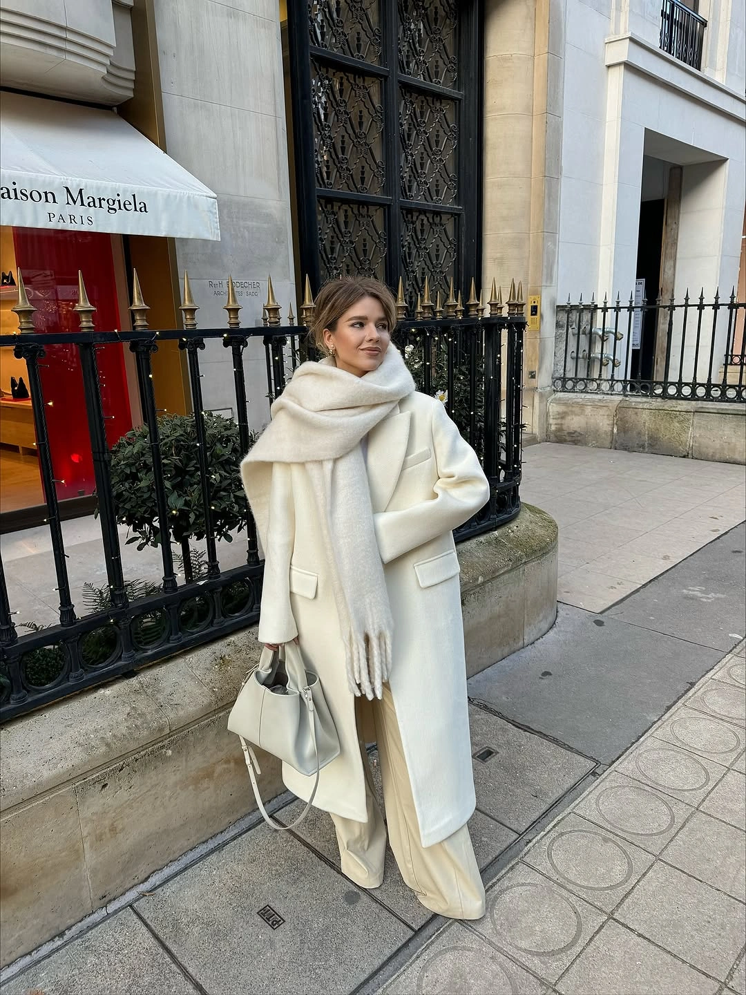 Cream scarf and coat with pale wide trousers and light handbag