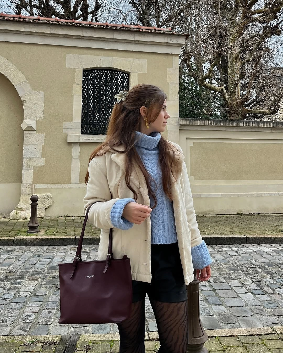 Cream jacket pale blue scarf brown trousers and large brown tote