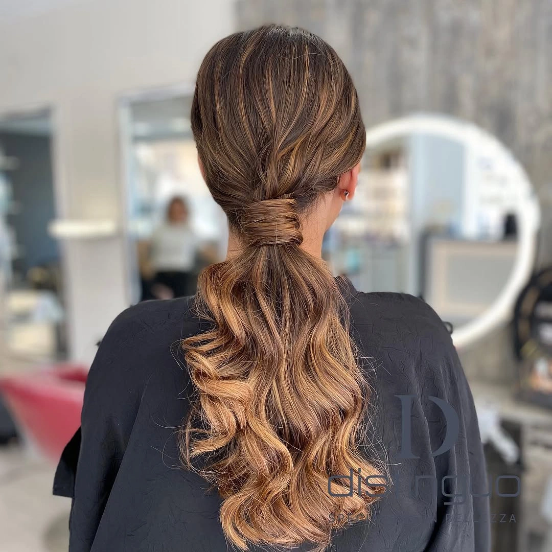 Low wrapped brunette ponytail with caramel ribbons through waves