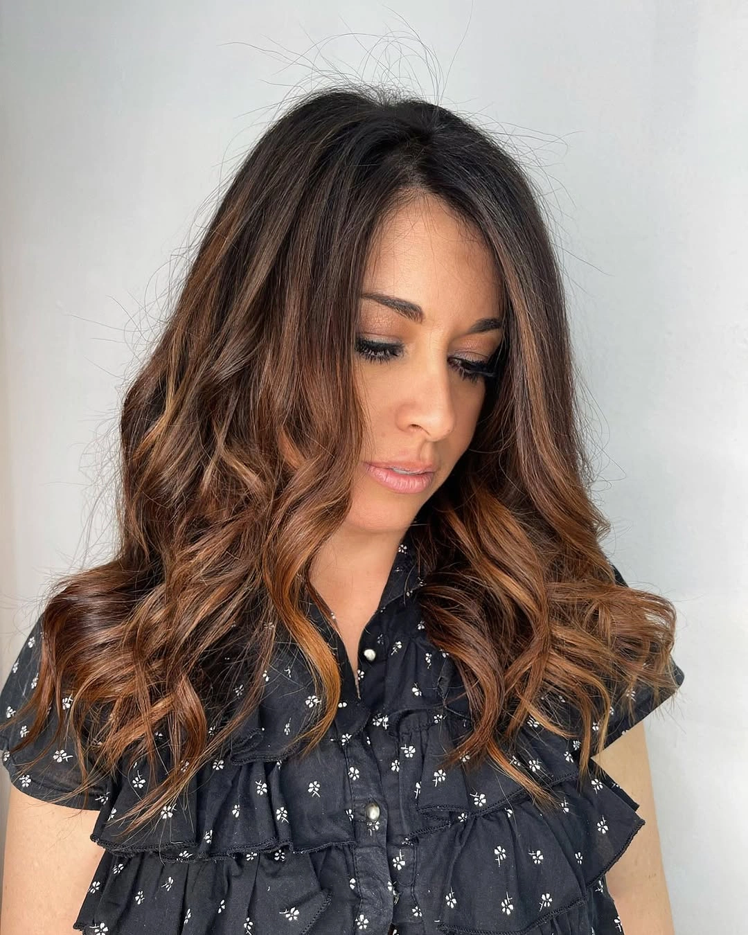 Curled brunette waves with dark roots and caramel copper ribbons