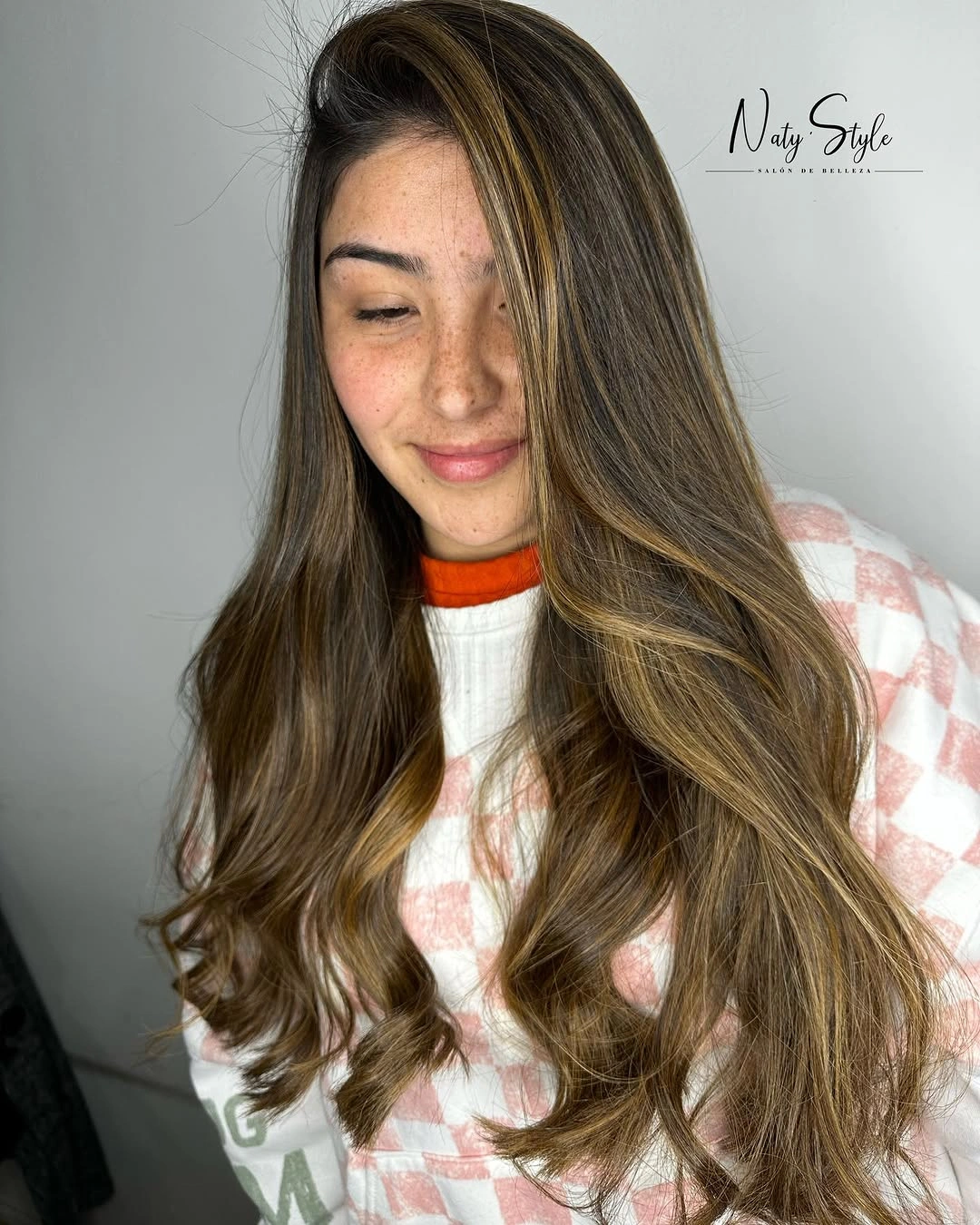 Long layered brunette waves with golden ribbons near the face