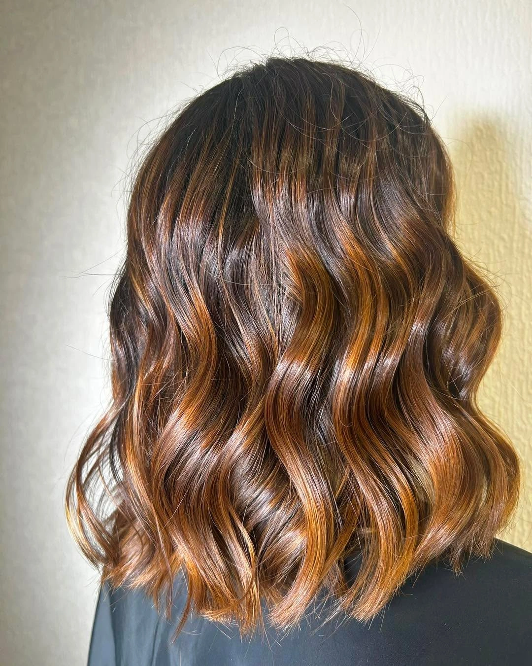 Shoulder-length brunette waves with copper and amber bands