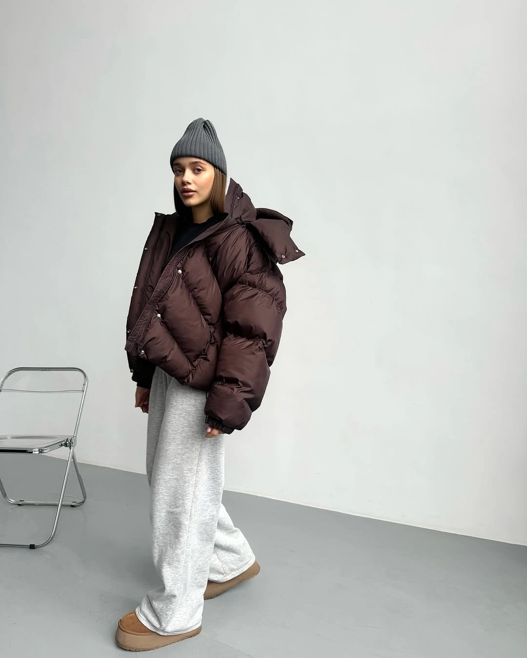 Dark plum puffer, gray ribbed beanie, pale wide-leg sweatpants, and tan ankle boots.