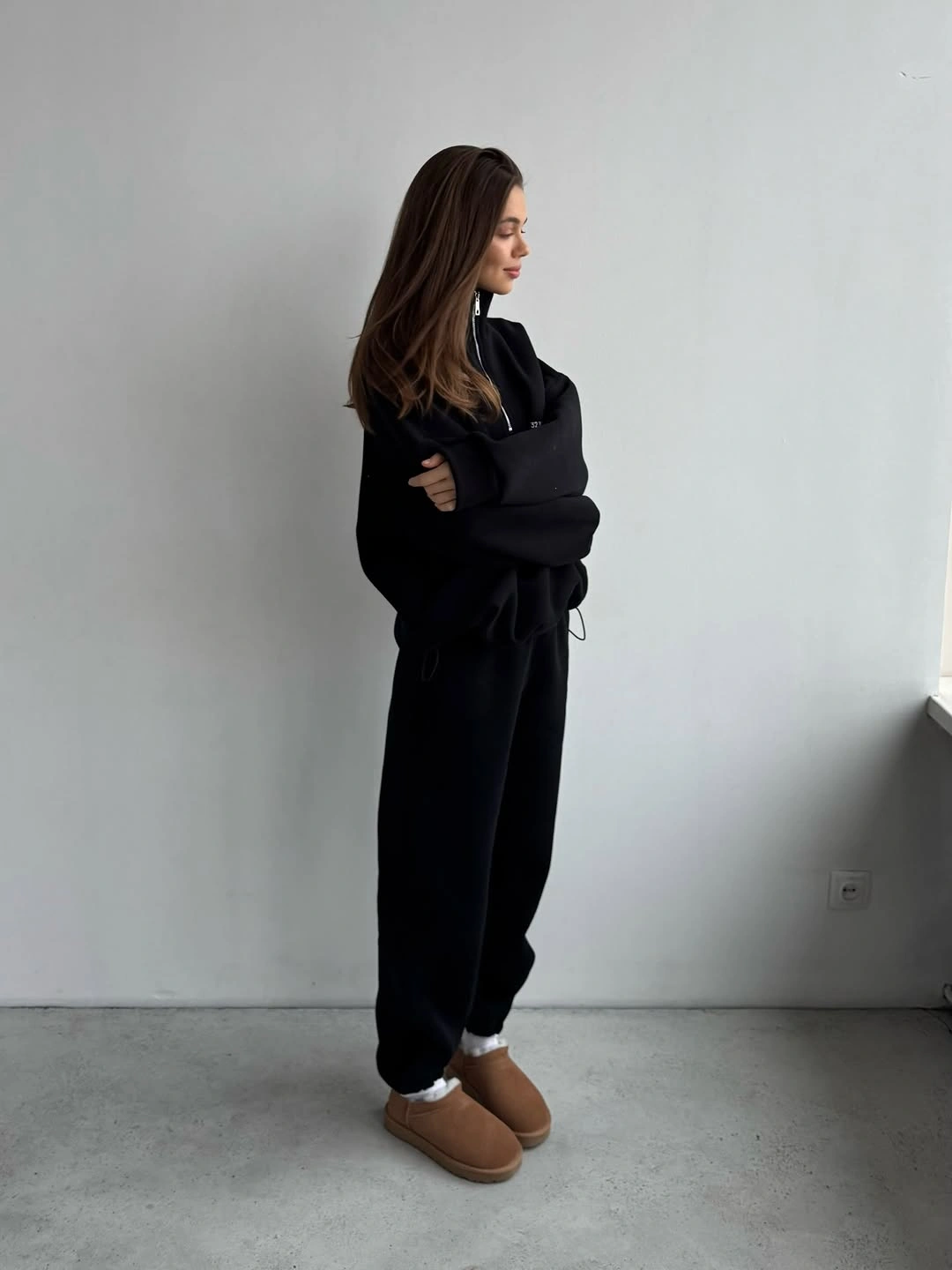 Oversized black hoodie and sweatpants with pale socks and brown ankle boots.