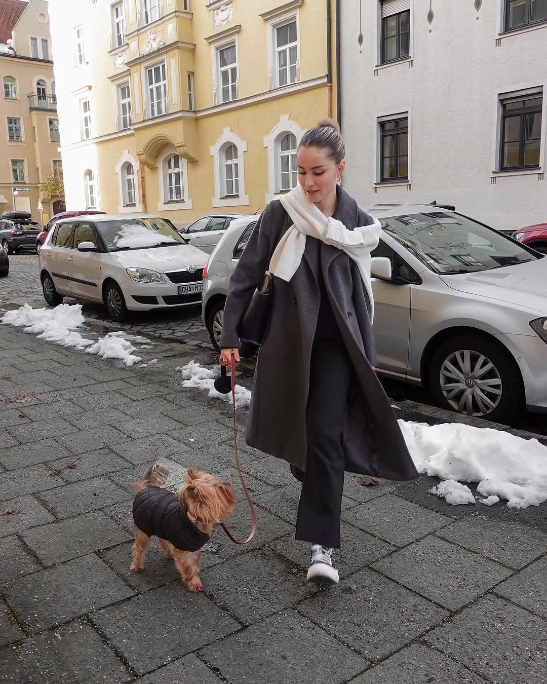 Charcoal coat, pale scarf, dark trousers, and sneakers
