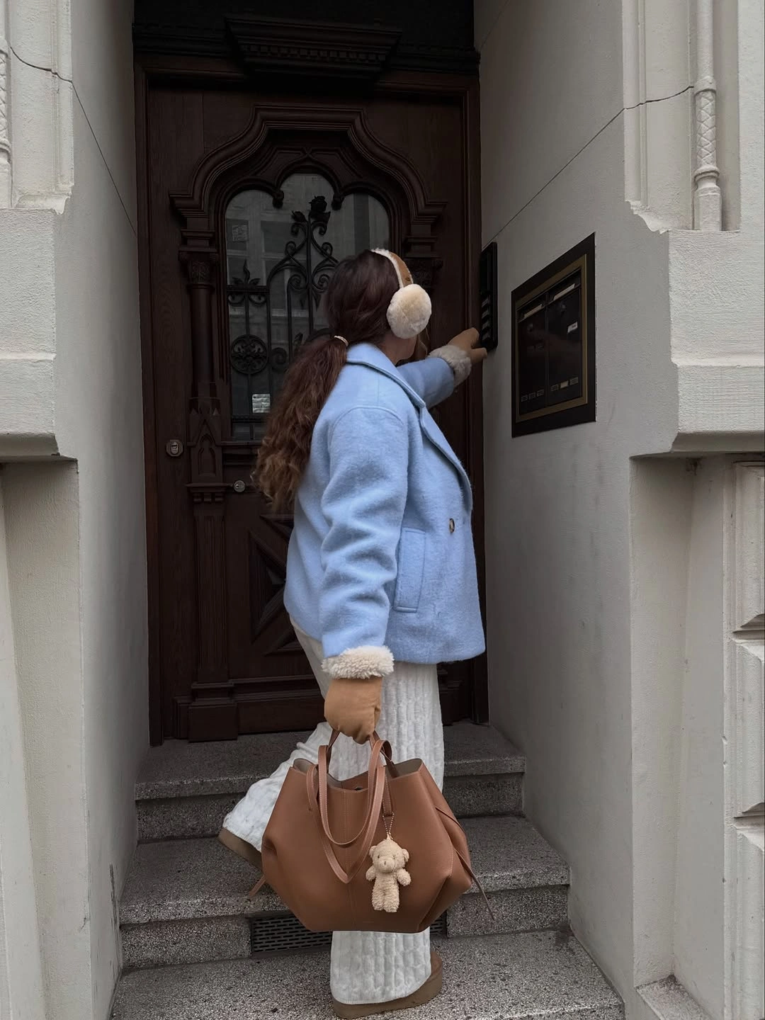 Pale blue coat, white skirt, earmuffs, and tan tote