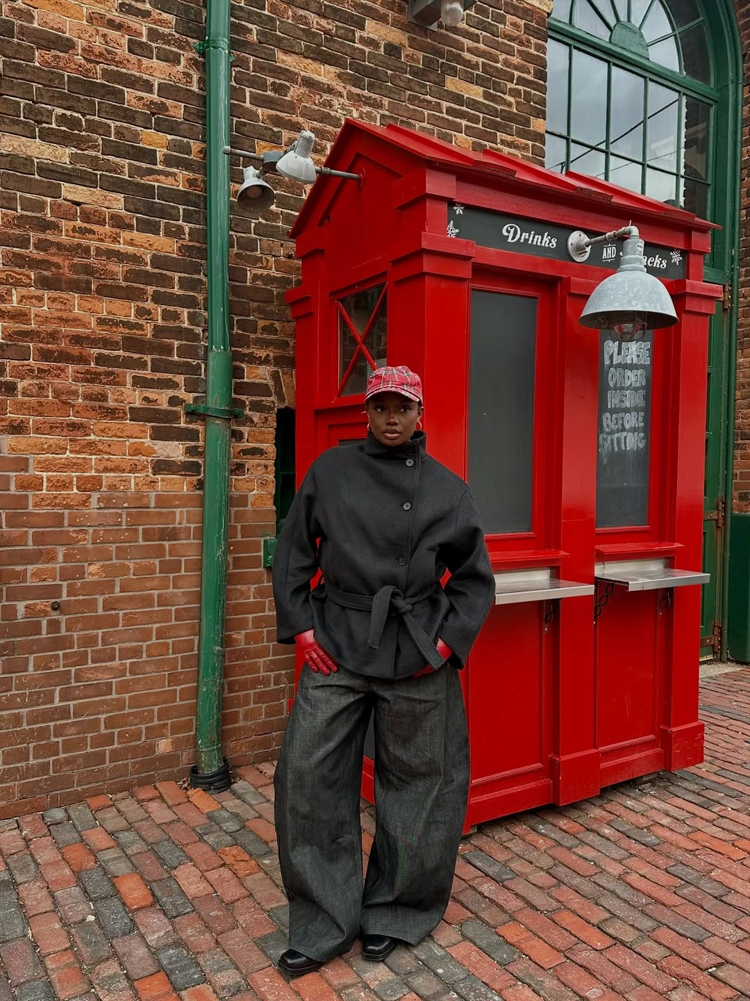 Dark gray belted jacket, wide trousers, red gloves, red cap