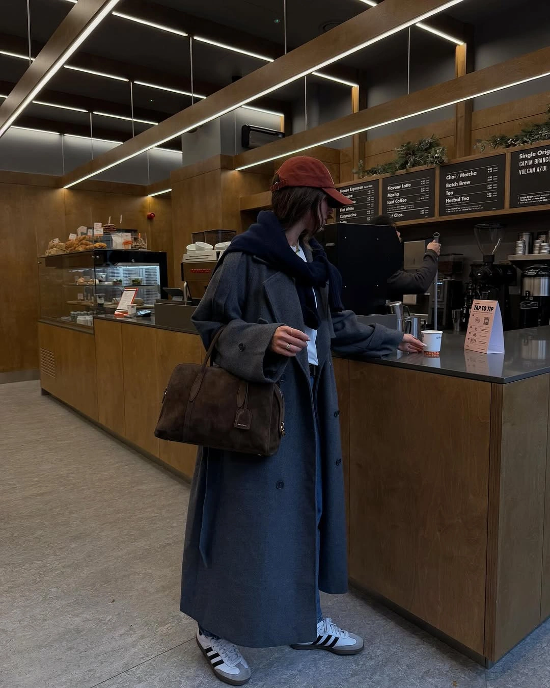 Blue-gray long coat, red cap, sneakers, and brown bag
