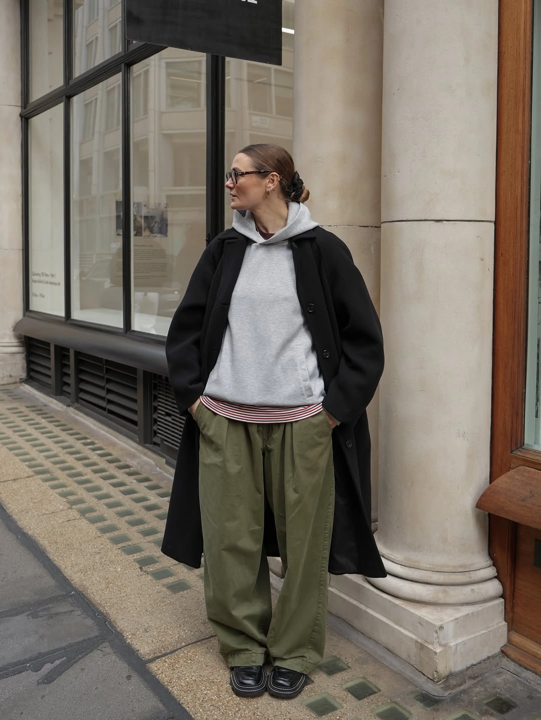 Black coat with gray hoodie, olive pants, and black shoes