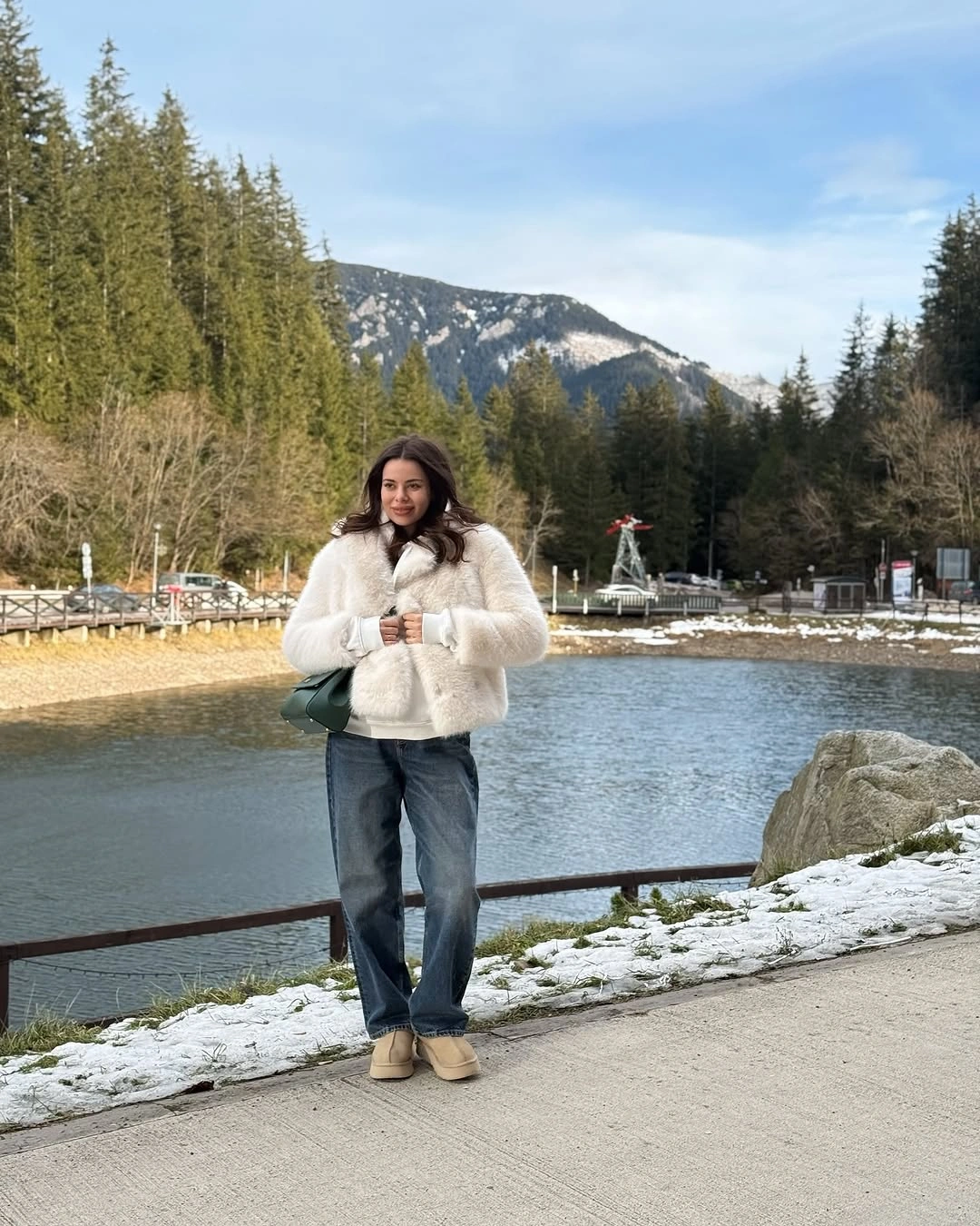 White fluffy jacket, blue jeans, beige boots, green bag