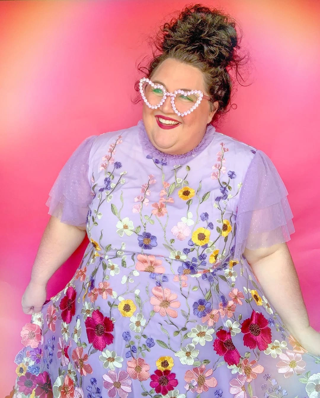High curly bun with heart-shaped glasses and floral dress